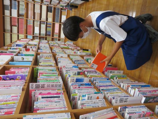 返却された本を書架に戻す作業をしている中学生