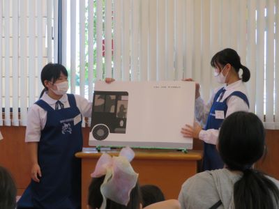 赤ちゃんタイムで大型絵本を読む2人の中学生